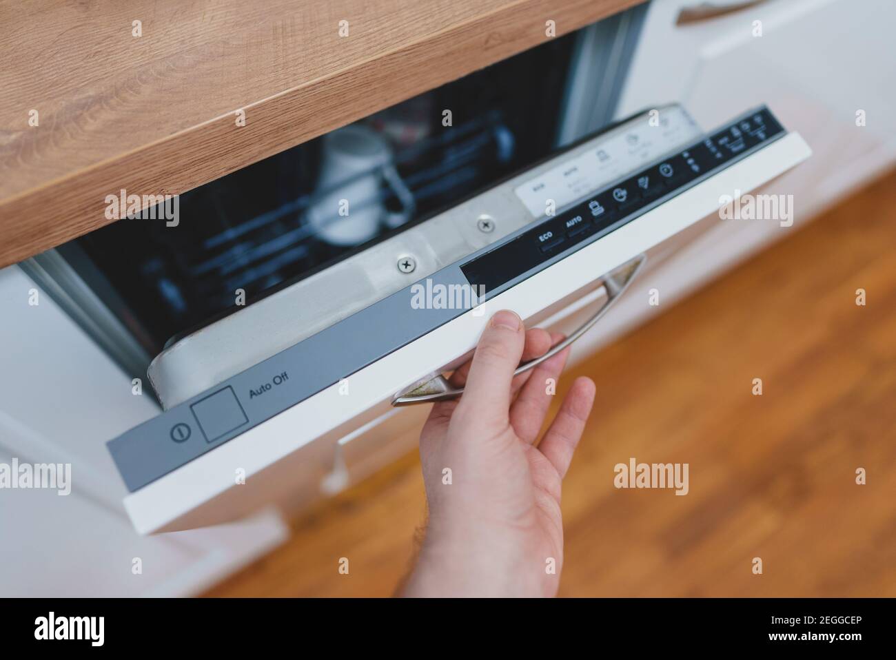 Mann öffnet oder schließt Geschirrspüler in der Küche. Stockfoto