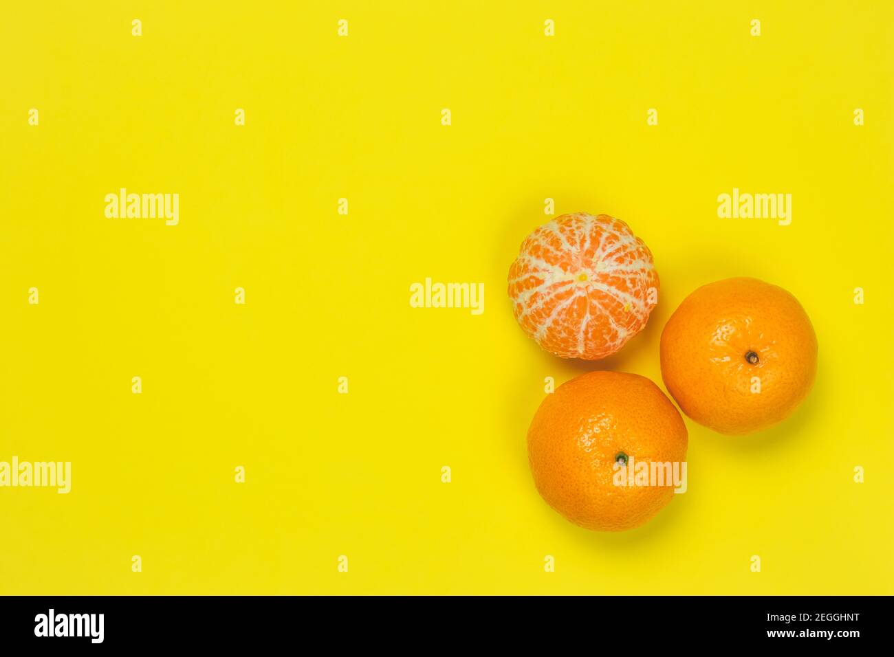Mandarinen auf gelbem Papierhintergrund. Heller Rahmen mit Mandarinen, Kopierraum für Text. Vorlage, Muster. Zitrusfrüchte Draufsicht. Lustige Sommerstimmung Stockfoto