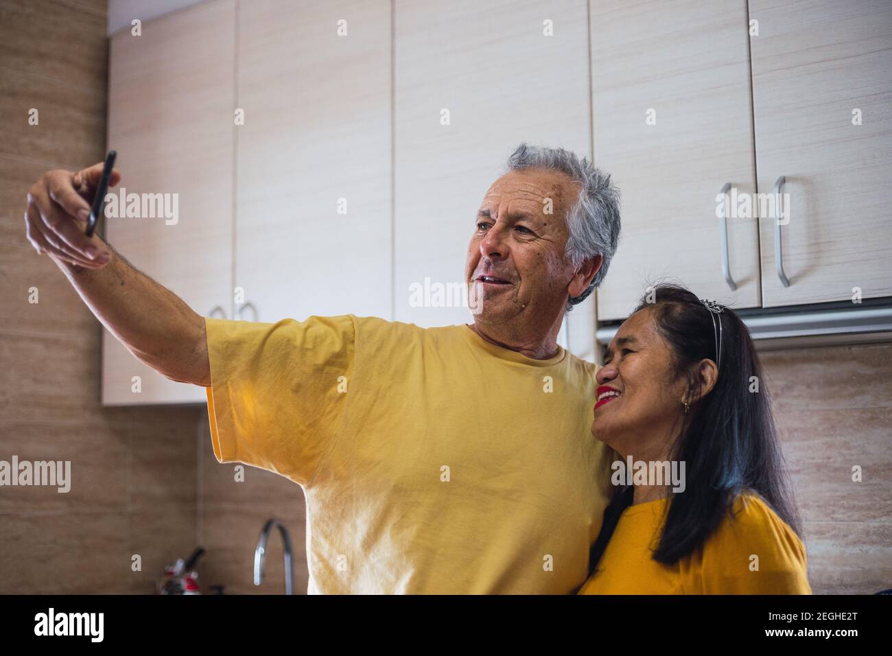 Match gelb mittleren Alters Paar nimmt ein Selfie Stockfoto