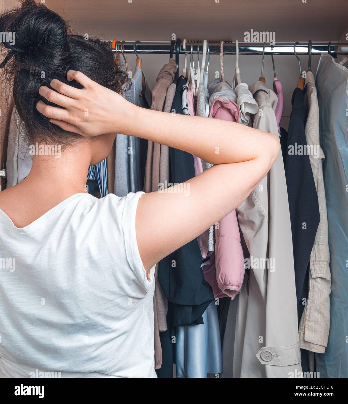 Die Frau wählt nachdenklich, was sie trägt. Stockfoto