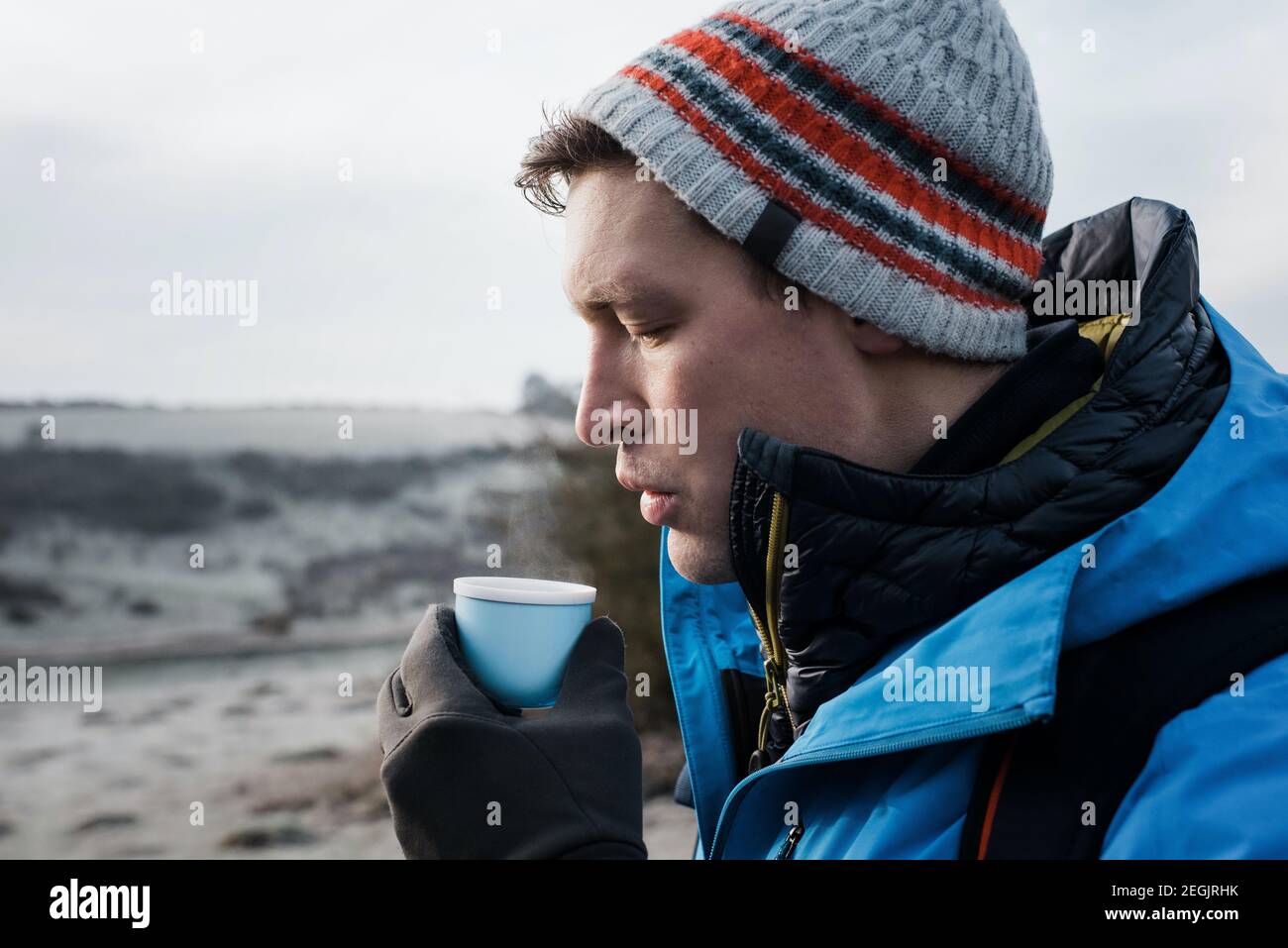 Mann bläst auf heißen Kaffee und nimmt eine Pause während des Spazierens In England Stockfoto