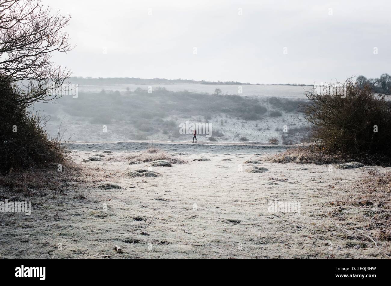 Frau, die auf einem frostigen Weg in der englischen Landschaft läuft Im Winter Stockfoto