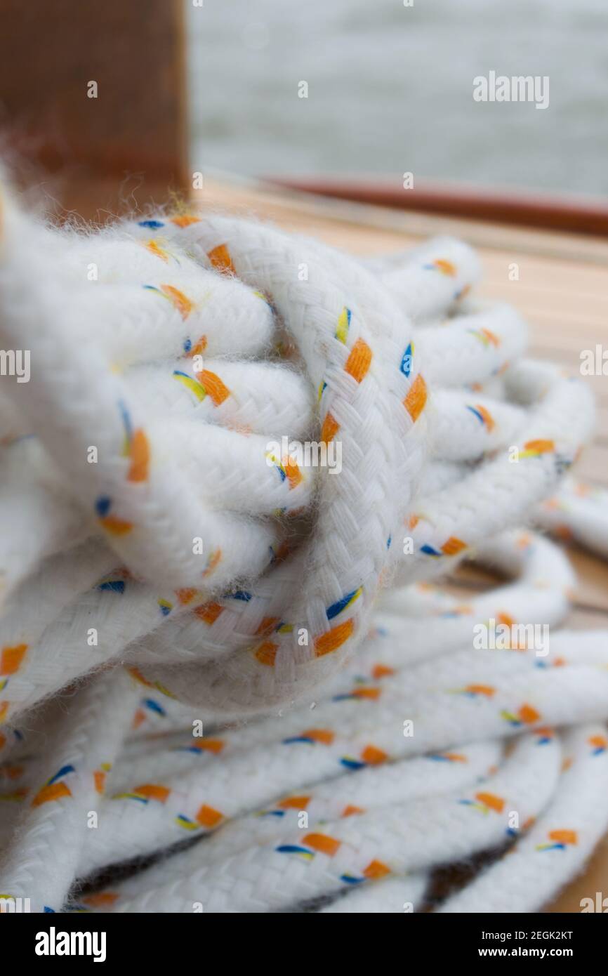 Detail einer gebundenen Spule aus weißem Seil mit gelben und blauen Flecken. In einem Haufen gerollt, dann in einem losen Knoten um sich geschlungen Stockfoto