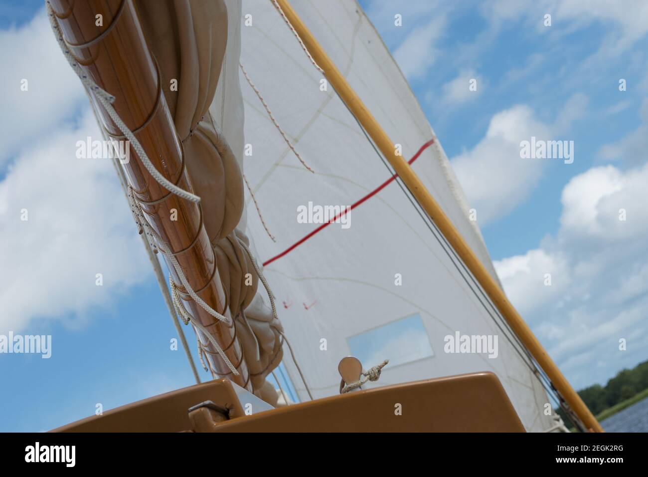 Detail der Unterseite des Booms auf einer Segelyacht, mit dem Jib (Vorsegel) gefüllt mit Wind und einem sonnigen blauen Himmel dahinter Stockfoto