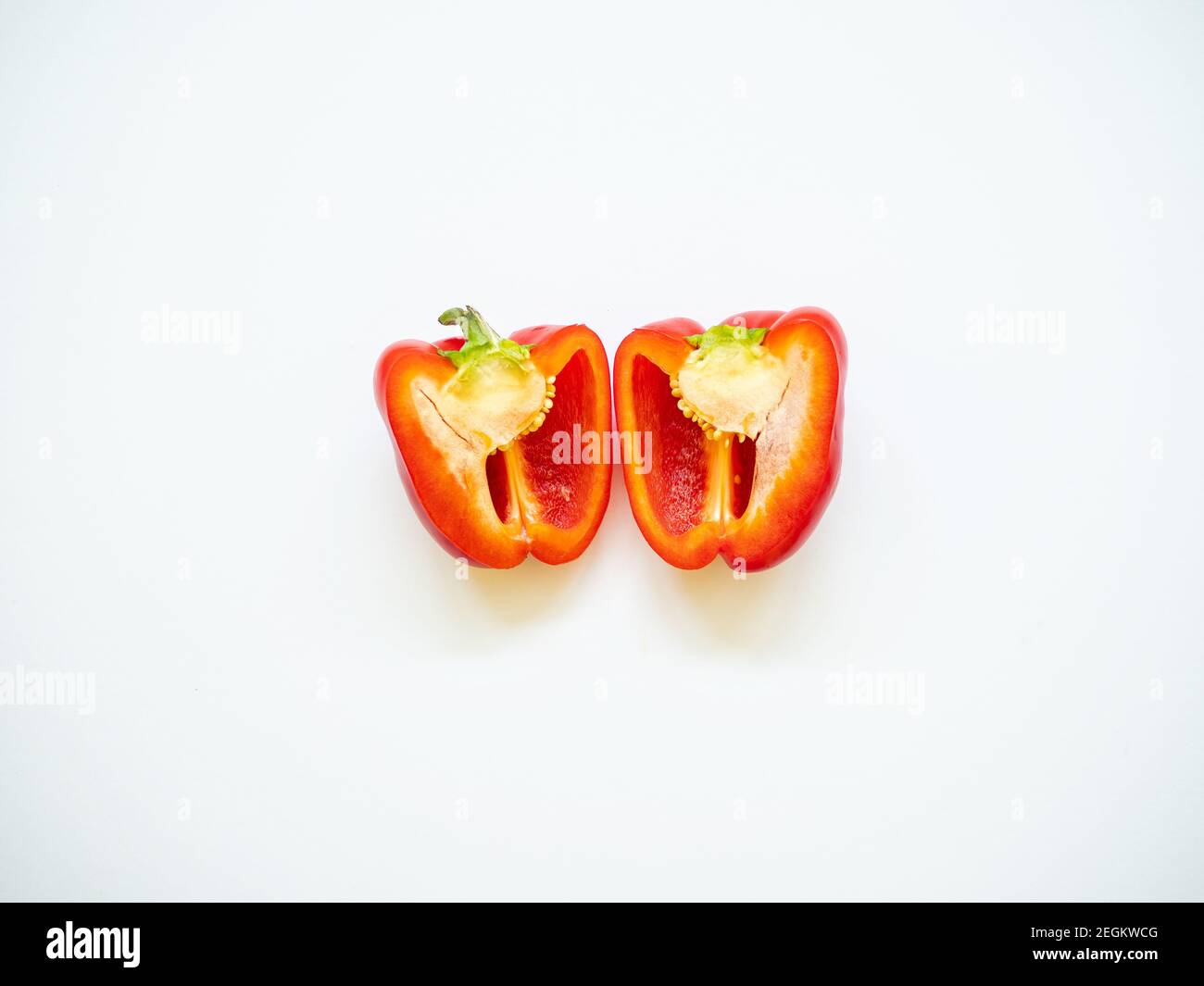 Rote Paprika in Scheiben geschnitten mit Samen in weißem Hintergrund isoliert Von oben betrachtet - Flatlay-Optik Stockfoto