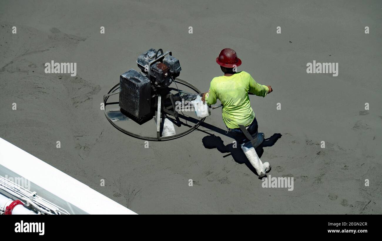 Arbeiter, der die Kelle mit der Kraft bis zum Beton benutzt Stockfoto
