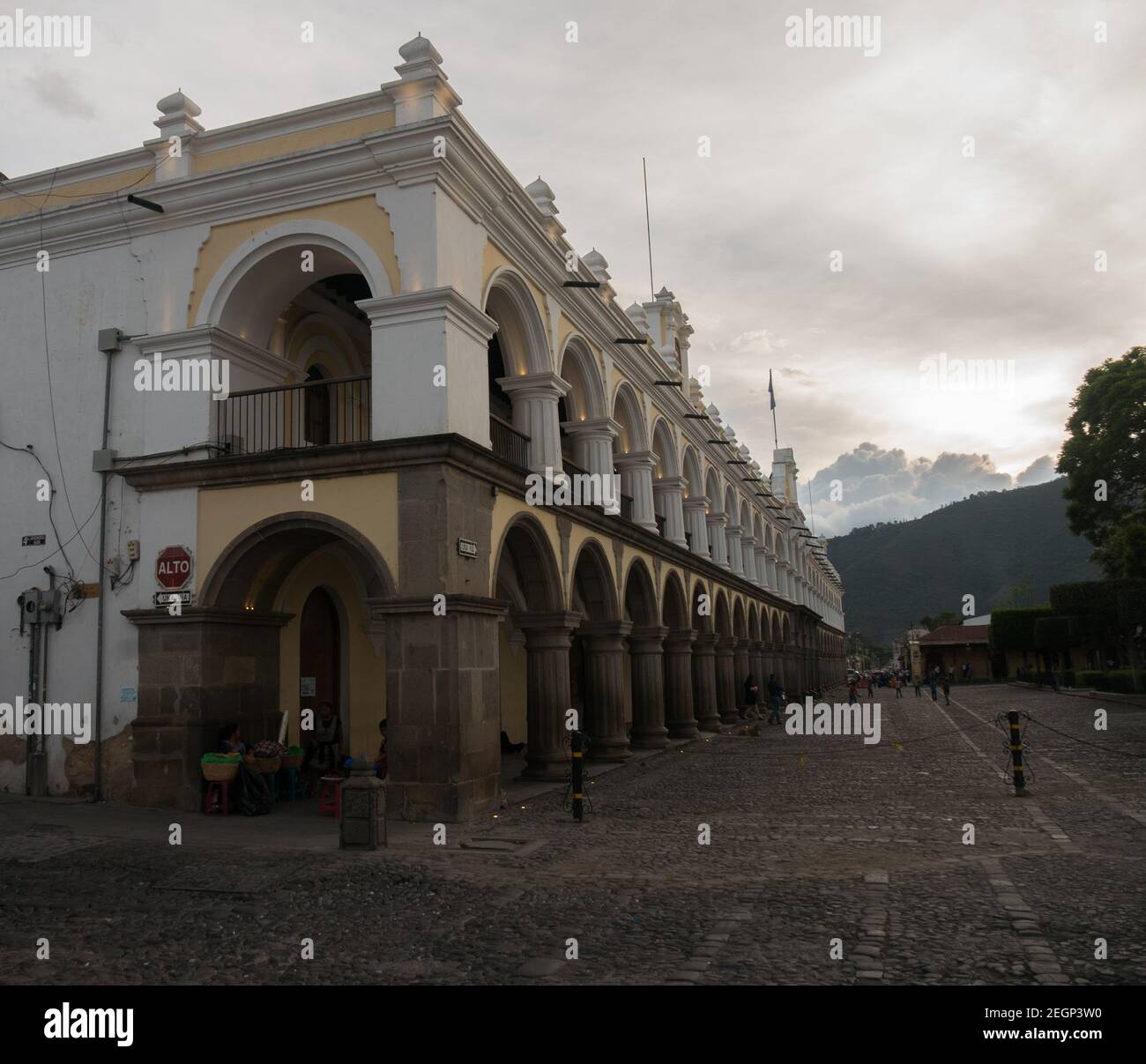 Guatemala, Antigua - 26. Mai 2019 - Palacio de los capitanes generales Gebäude, Antigua Stadtzentrum, einheimische Straßenhändler, Berge im Hintergrund Stockfoto