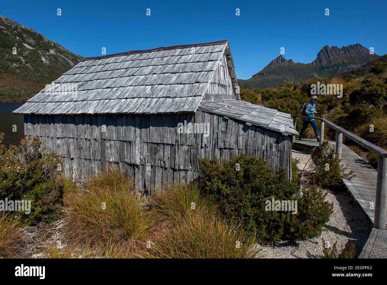 Ein Tourist spaziert am Boat Shed am Dove Lake im Cradle Mountain-Lake St Clair National Park in Tasmanien, Australien, vorbei. Stockfoto