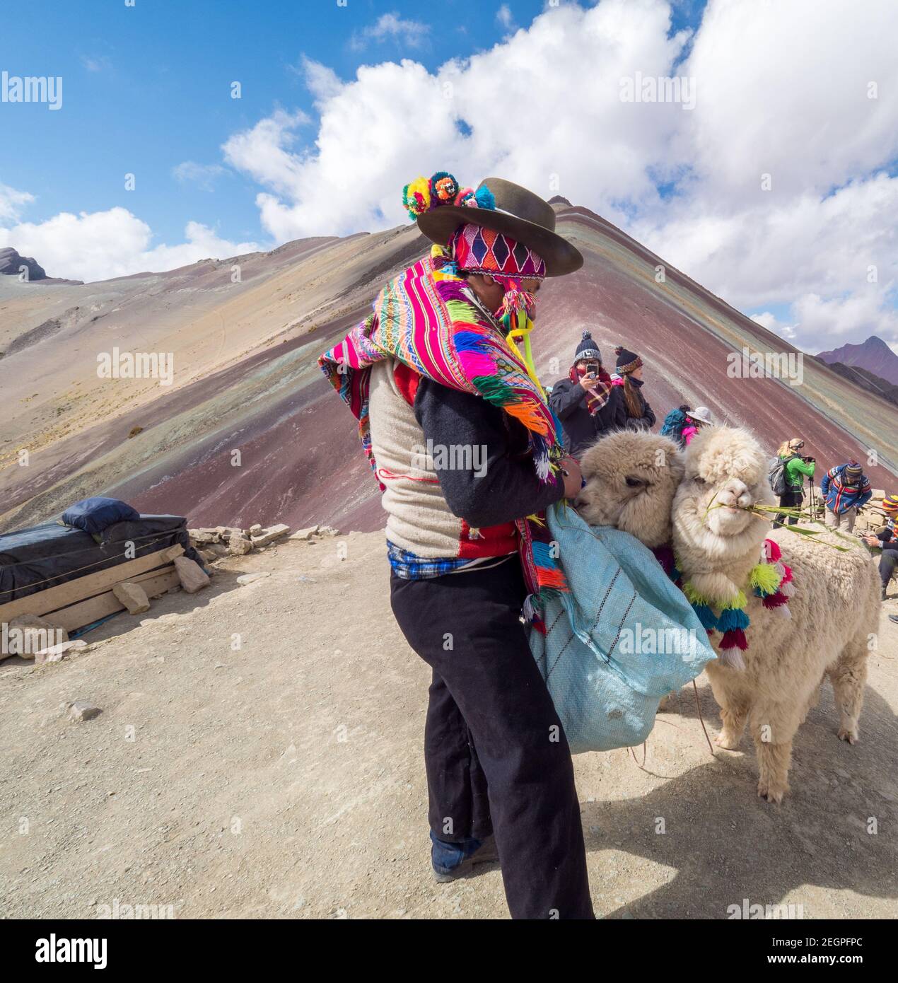 Peru, Vinicunca - 27. September 2019 - Inder in leuchtenden Farben gekleidet füttert Lama am Sieben Farben Berg Stockfoto