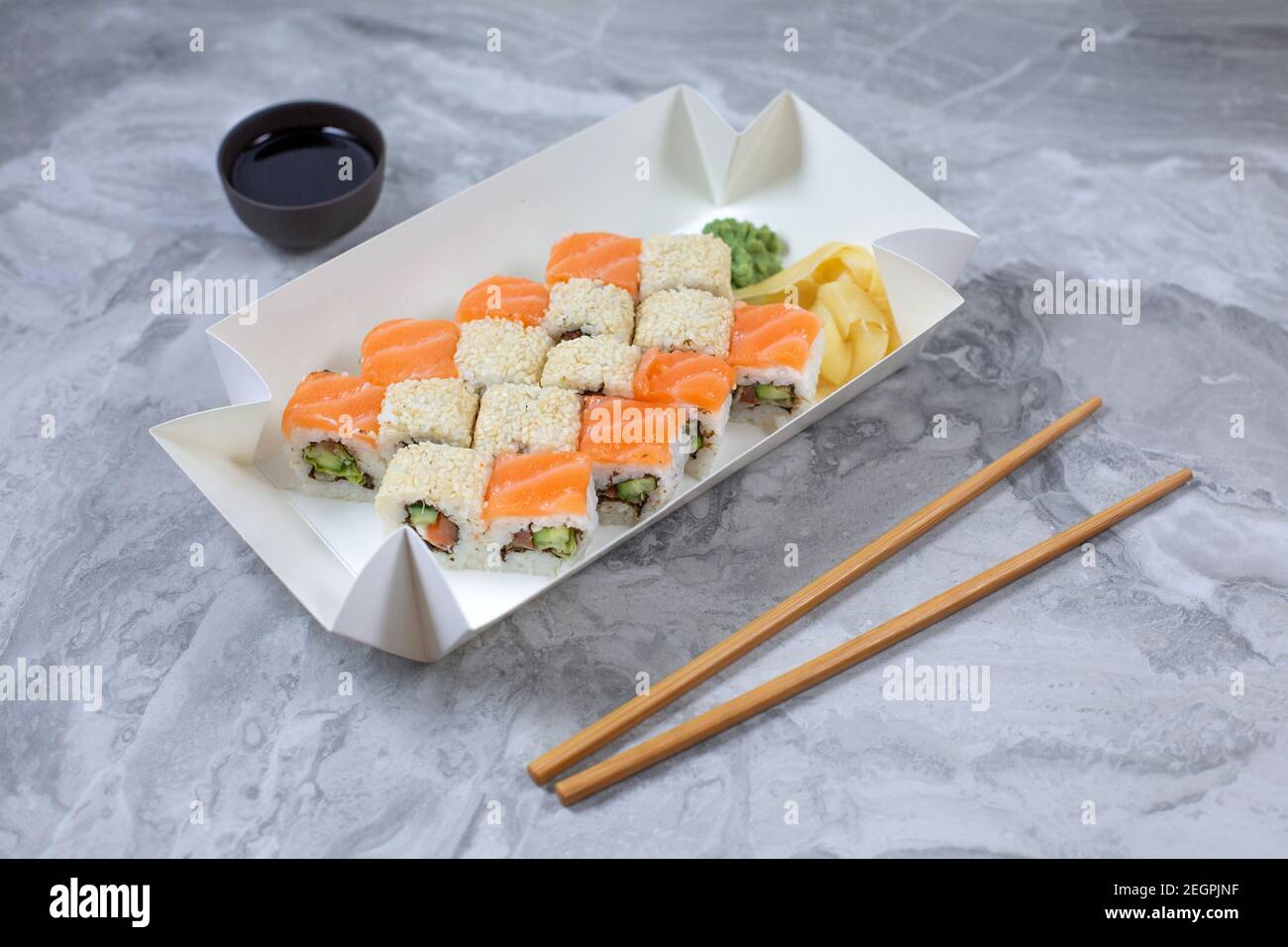 Takeaway-Box mit Sushi-Rollen auf Steintisch. Sushi-to-go-Konzept. Stockfoto