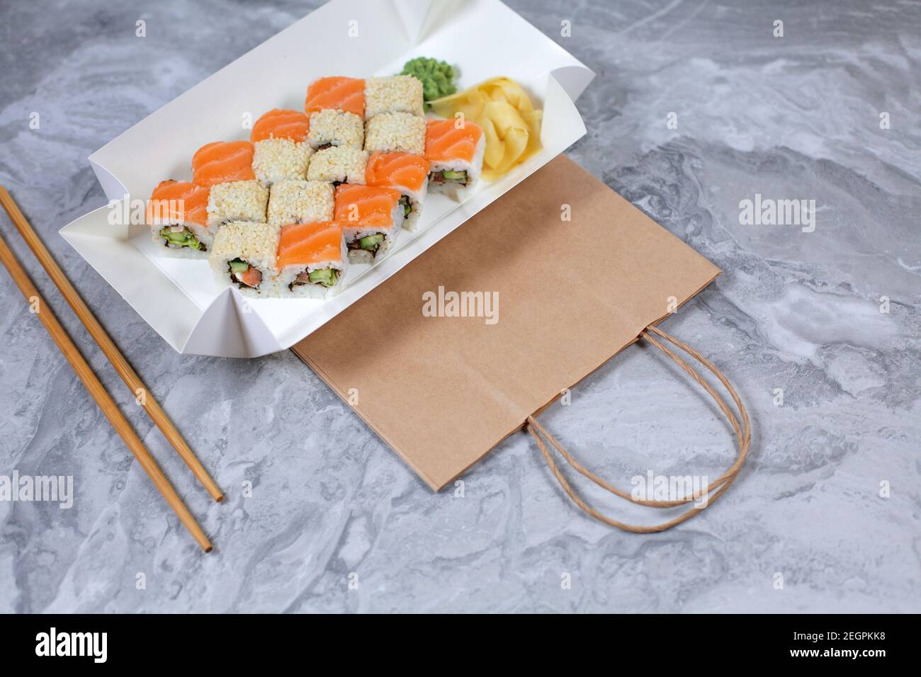 Takeaway-Box mit Sushi-Rollen auf braunem Papierbeutel. Sushi-to-go-Konzept. Stockfoto