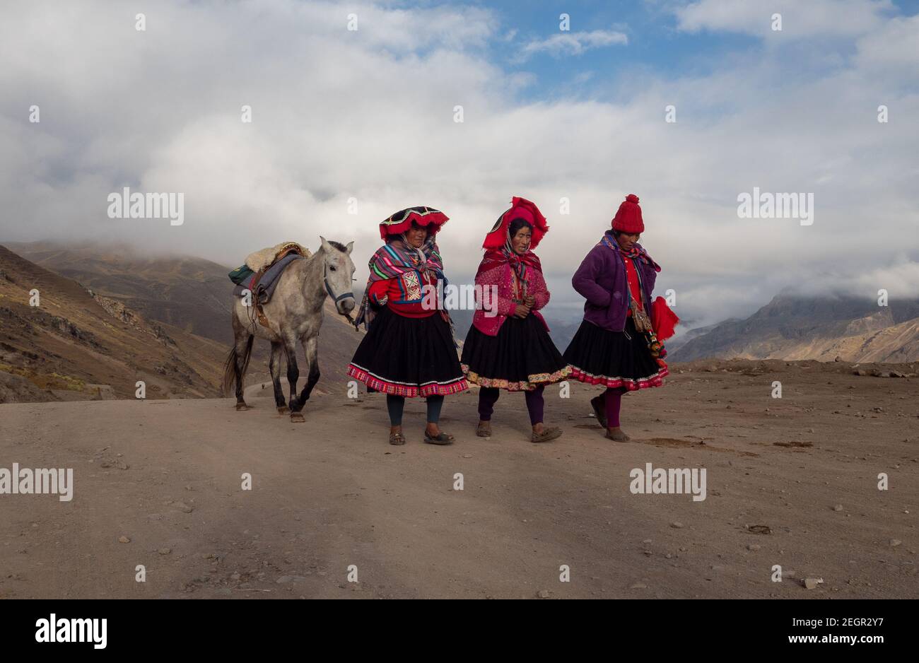 Peru, Vinicunca - 1. Oktober 2019 - drei gebürtige Frauen gehen und reden ein Pferd zu führen, während sie auf einer unbefestigten Straße in traditioneller Kleidung gehen Stockfoto