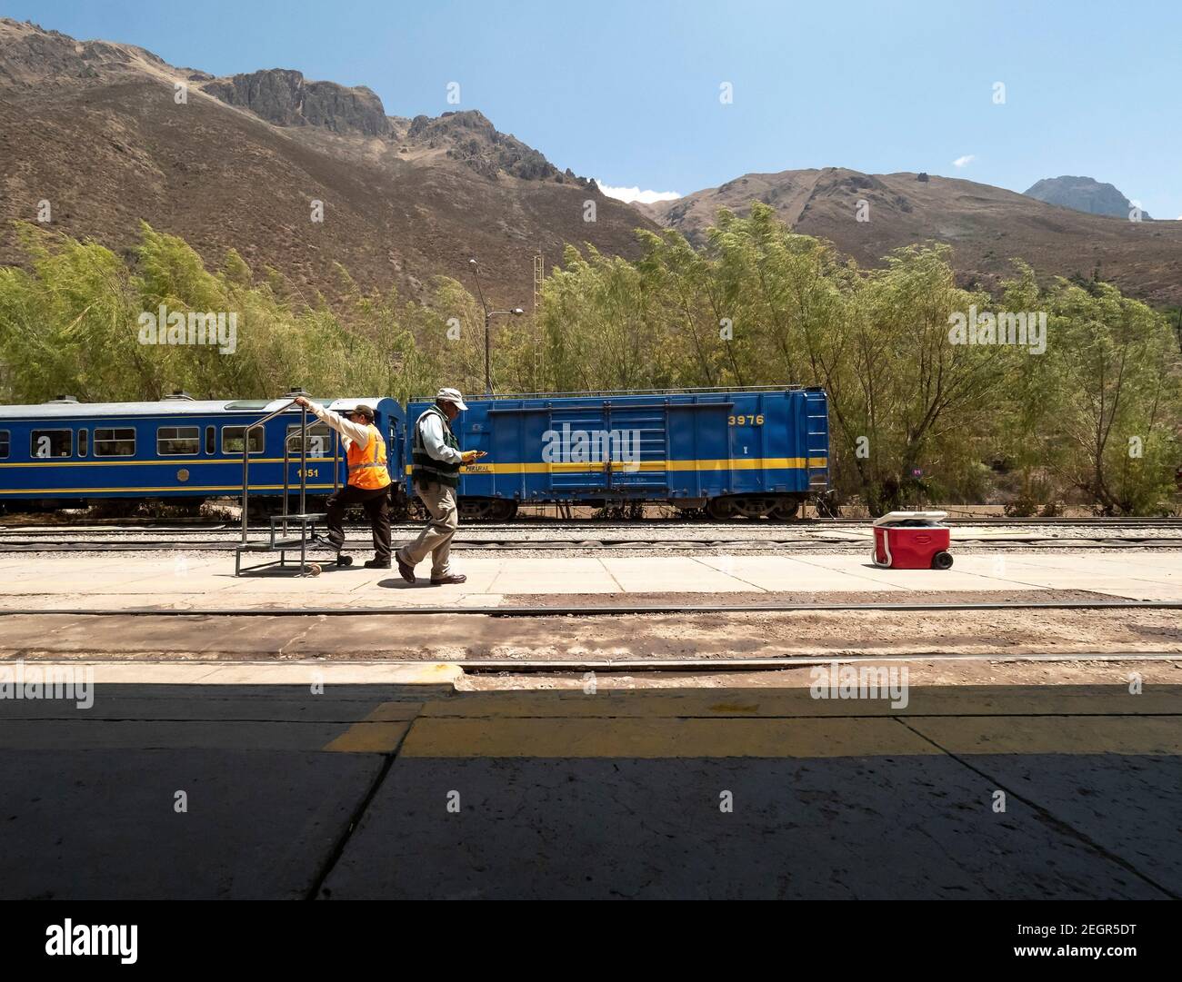 Peru, Machupicchu - 25. September 2019- Arbeiter am Bahnhof Ollantaytambo Bahngleise, blaue Inkarail-Waggons im Hintergrund Stockfoto