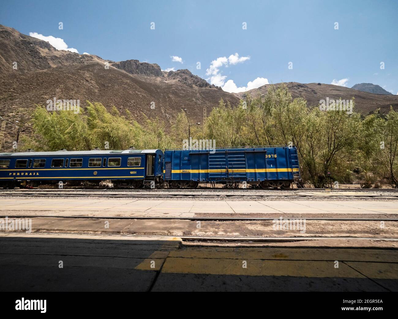 Peru, Machupicchu - 25. September 2019 - Blue Incarail Zug am Bahnhof Oyantaytambo, Bergkette unter blauem Himmel Stockfoto