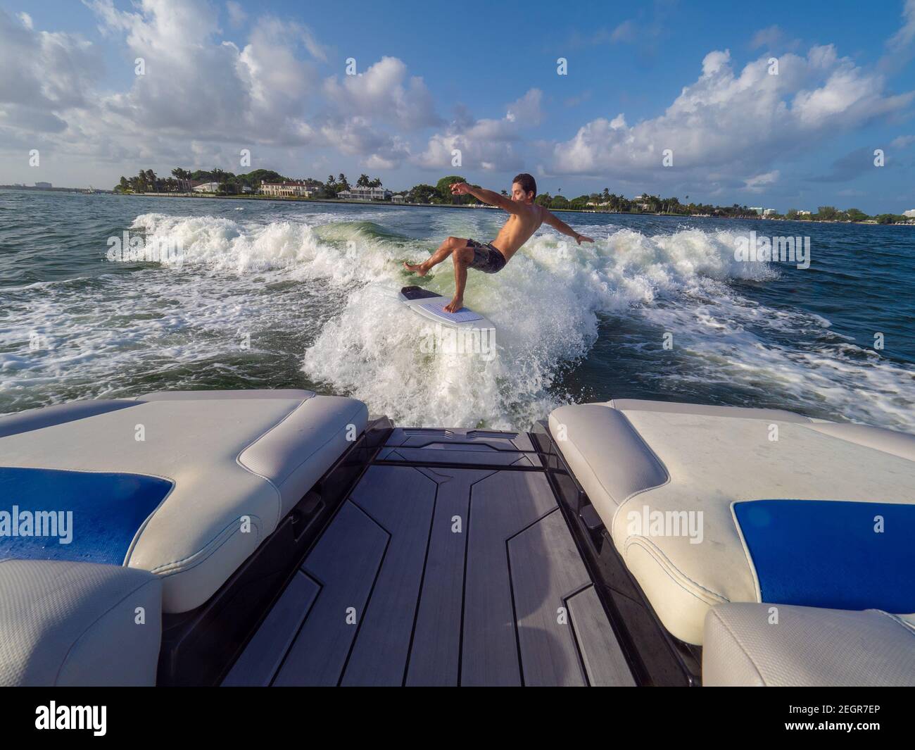 Athletischer Rüde fällt vom Brett während Wakesufing auf See, Rückseite des Bootes im Rahmen Stockfoto