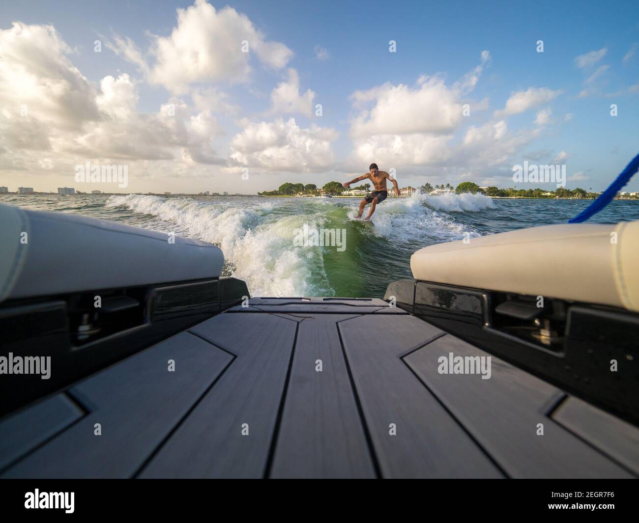 Männliche Wakesurfing Welle hinter Boot auf See Stockfoto