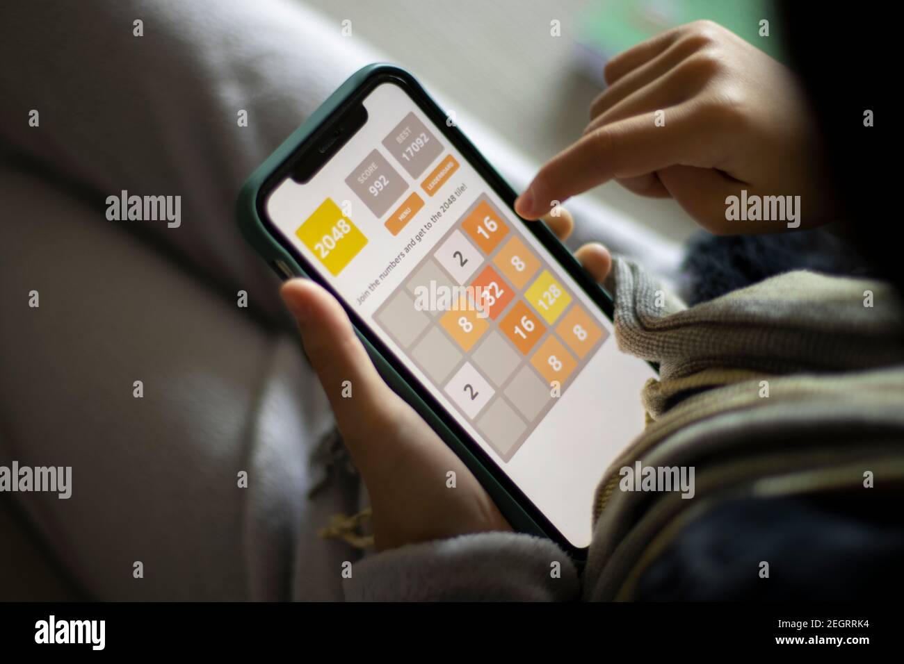 Ein Mädchen spielt das Spiel 2048 auf einem iPhone am 15. Februar 2021. Das Mathe-basierte Puzzle-Spiel wurde von Gabriele Cirulli geschrieben und auf GitHub veröffentlicht. Stockfoto