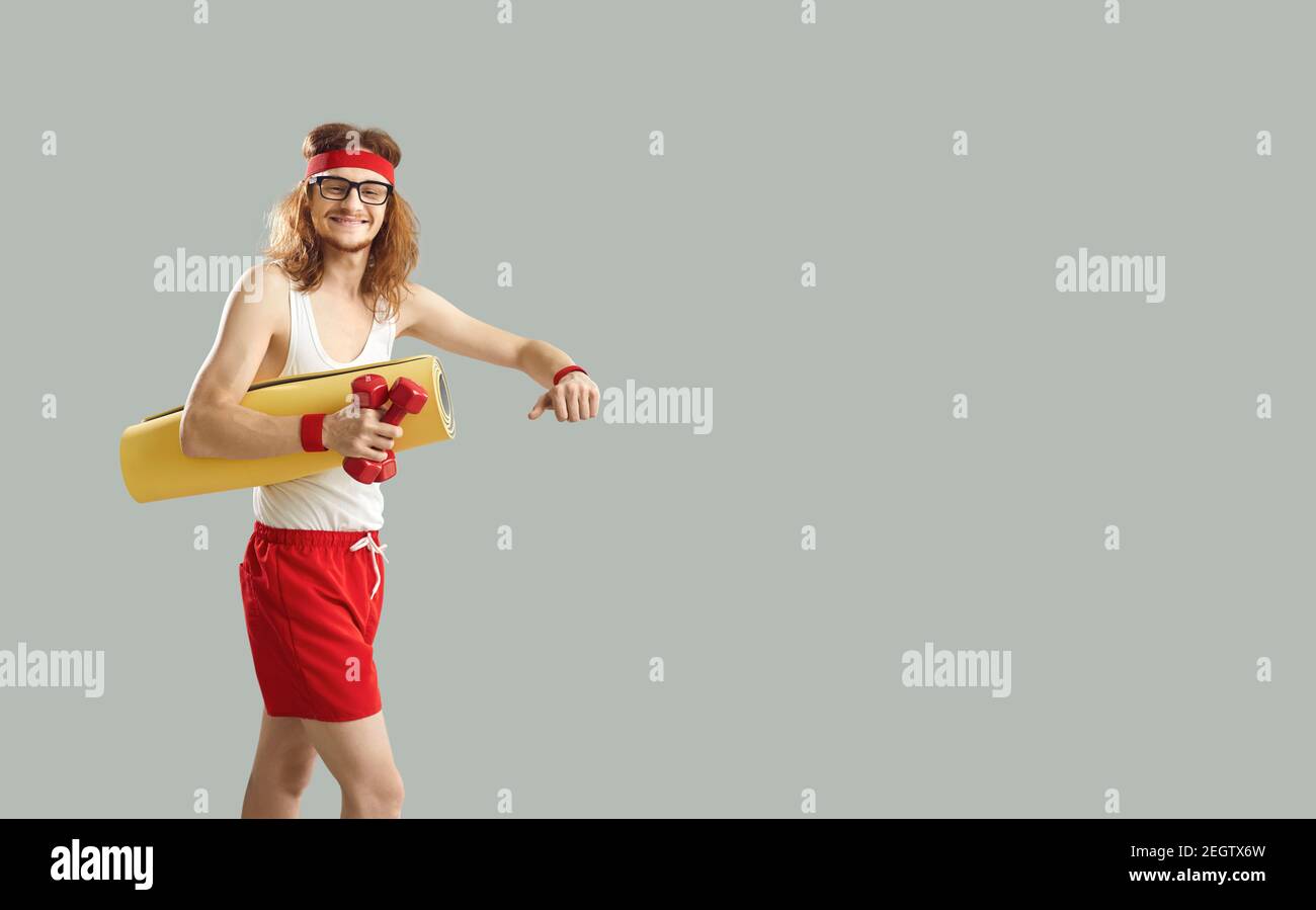 Fröhlicher Hipster junger Mann in rot und weiß Sportswear Walking Mit Humbbels und Skateboard Stockfoto