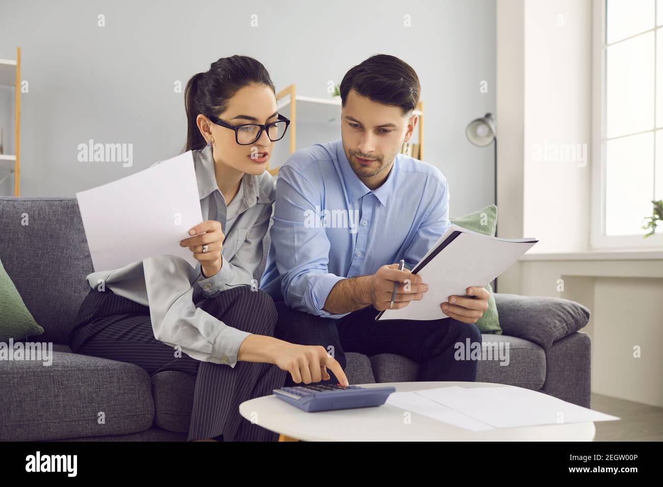 Junges Paar sitzt auf dem Sofa, Ausfüllen der Steuererklärung oder Blick durch Stromrechnungen Stockfoto