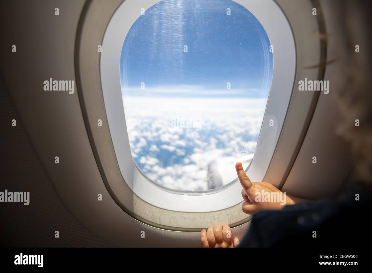 Nettes Kleinkind zeigt seinen Finger auf den Himmel durch das Fenster. First Flight Konzept, Reisen mit Kindern Stockfoto