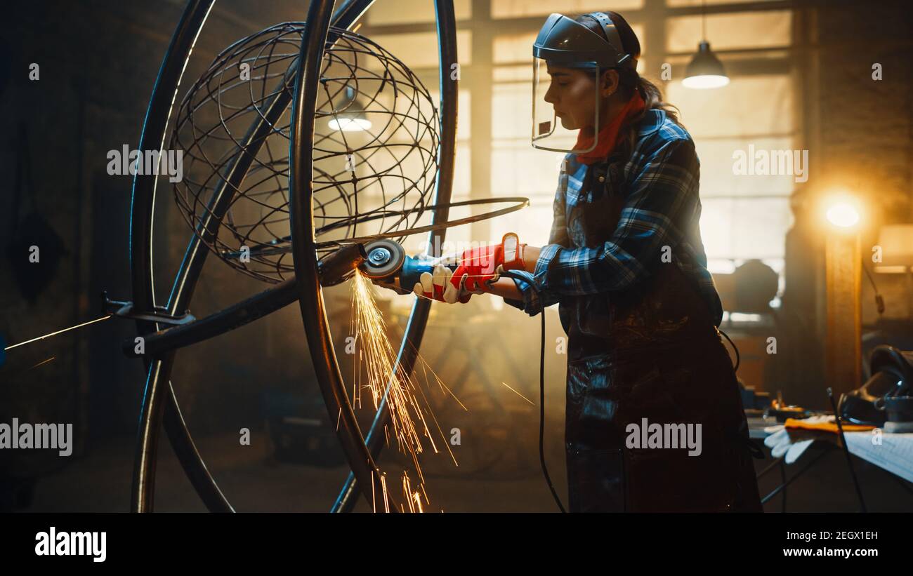 Talented Emerging Female Artist verwendet einen Disc Grinder, um eine abstrakte, brutale Metallskulptur zu machen, die den gegenwärtigen Moment widerspiegelt. Wunderschöner Tomboy Stockfoto