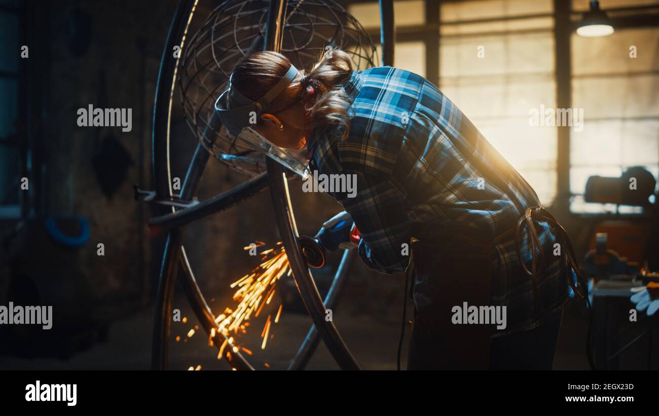 Talented Emerging Female Artist verwendet einen Disc Grinder, um eine abstrakte, brutale Metallskulptur zu machen, die den gegenwärtigen Moment widerspiegelt. Wunderschöner Tomboy Stockfoto