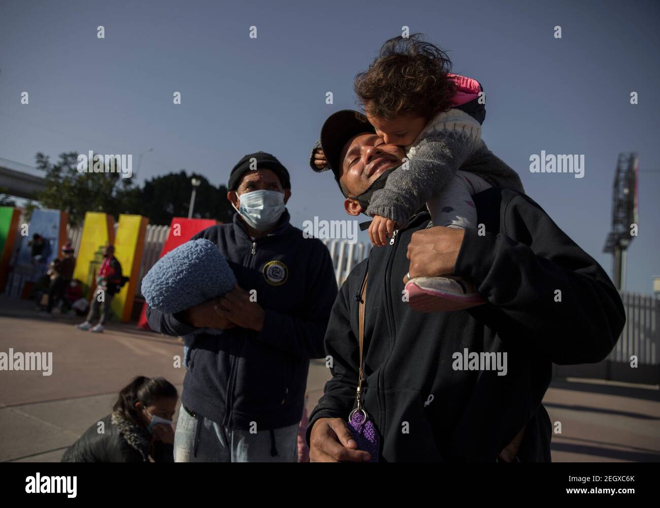 18. Februar 2021, Mexiko, Tijuana: Ein Mann zentralamerikanischer Herkunft hält seinen Sohn, nachdem er am Grenzübergang protestiert hat. Zentralamerikanische und mexikanische Migranten, die Flüchtlinge im Flüchtlingsheim Agape sind, demonstrierten vor dem Haupteingang des Grenzübergangs El Chaparral an der Grenze zwischen Tijuana, Mexiko, Und San Diego, Kalifornien, mit dem Ziel, die US-Behörden zu bitten, die Grenze zu öffnen und den Prozess der Gewährung von politischem Asyl für Flüchtlinge neu zu starten. Nach dem Richtungswechsel in der Migrationspolitik erlaubt die US-Regierung erneut Asylsuchende über die Grenze. So Stockfoto