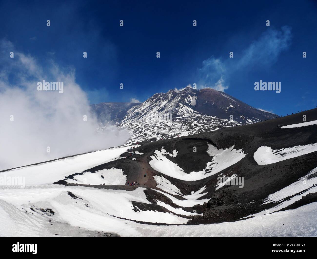 April 2019 Ätna: Schnee auf warm gehärteter Lava bei Rifugio Sapienza. Touristen dürfen herumlaufen. Stockfoto