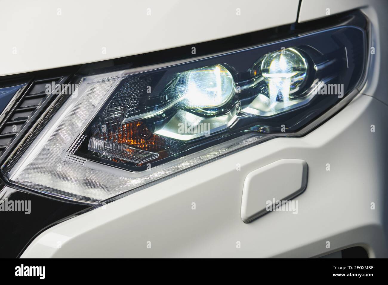 Scheinwerfer im weißen Auto Nahaufnahme. Fahrzeugscheinwerfer echtes Foto. Polnische Auto Licht Service Stockfoto