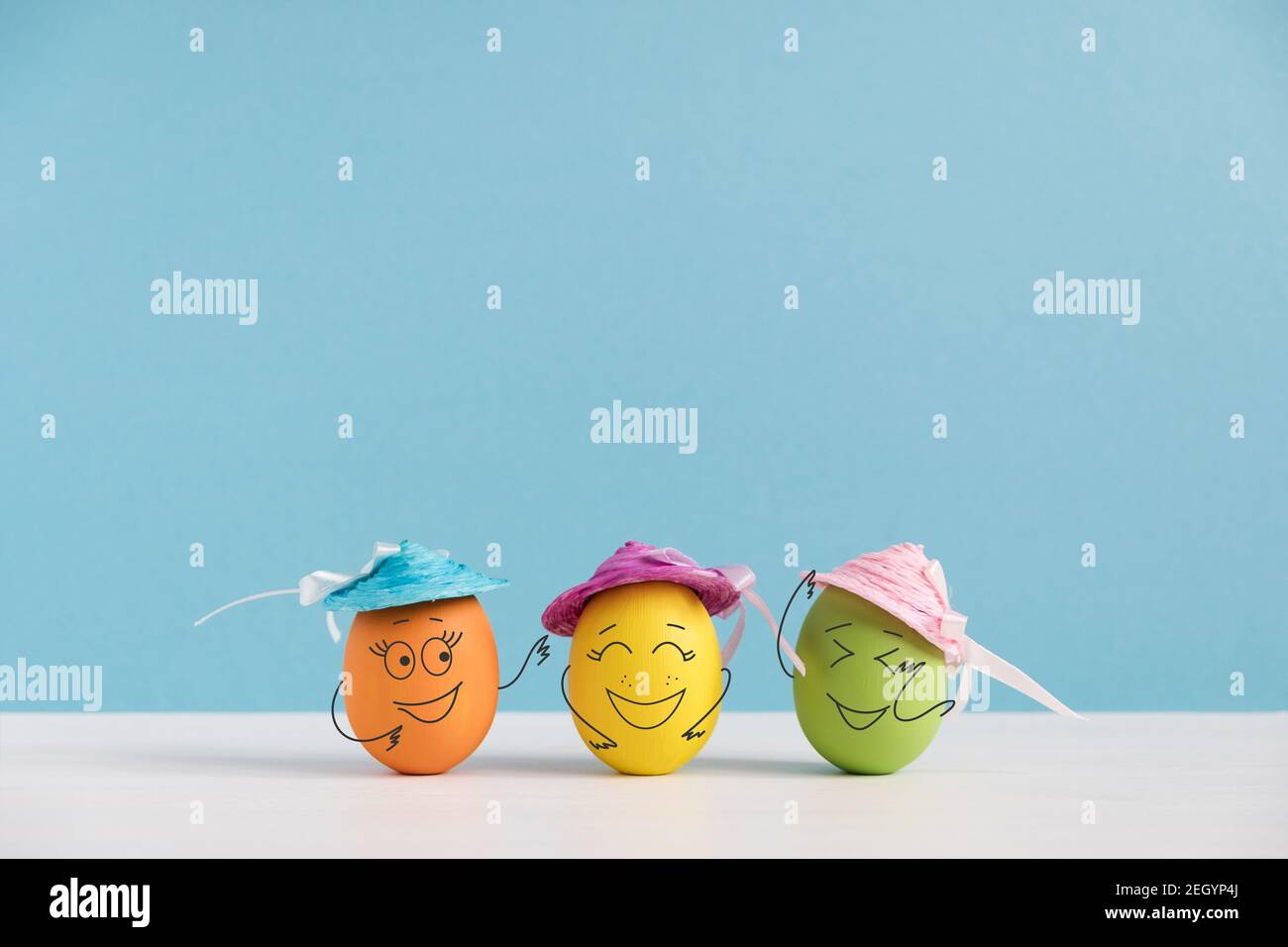 Glückliche Eier in Hüten lachen. Osterfeiertagskonzept mit niedlichen Eiern mit lustigen Gesichtern. Verschiedene Emotionen und Gefühle. Stockfoto