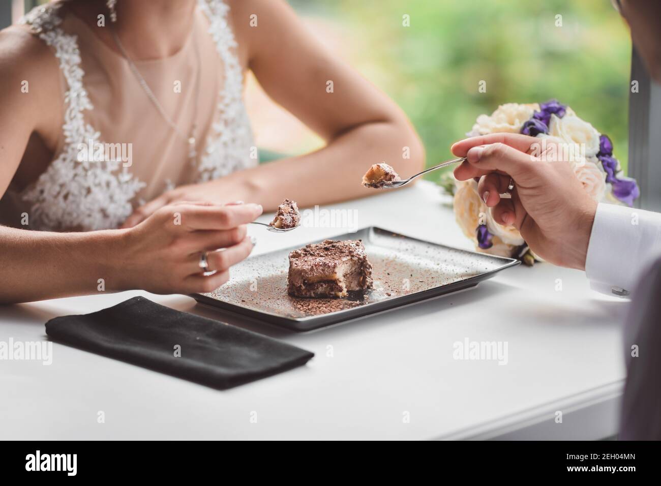 Ein verliebte Paar in einem Café, das einen Kuchen isst. Ein Liebesdatum in einem Restaurant. Hände Nahaufnahme nehmen Eis oder Dessert. Stockfoto