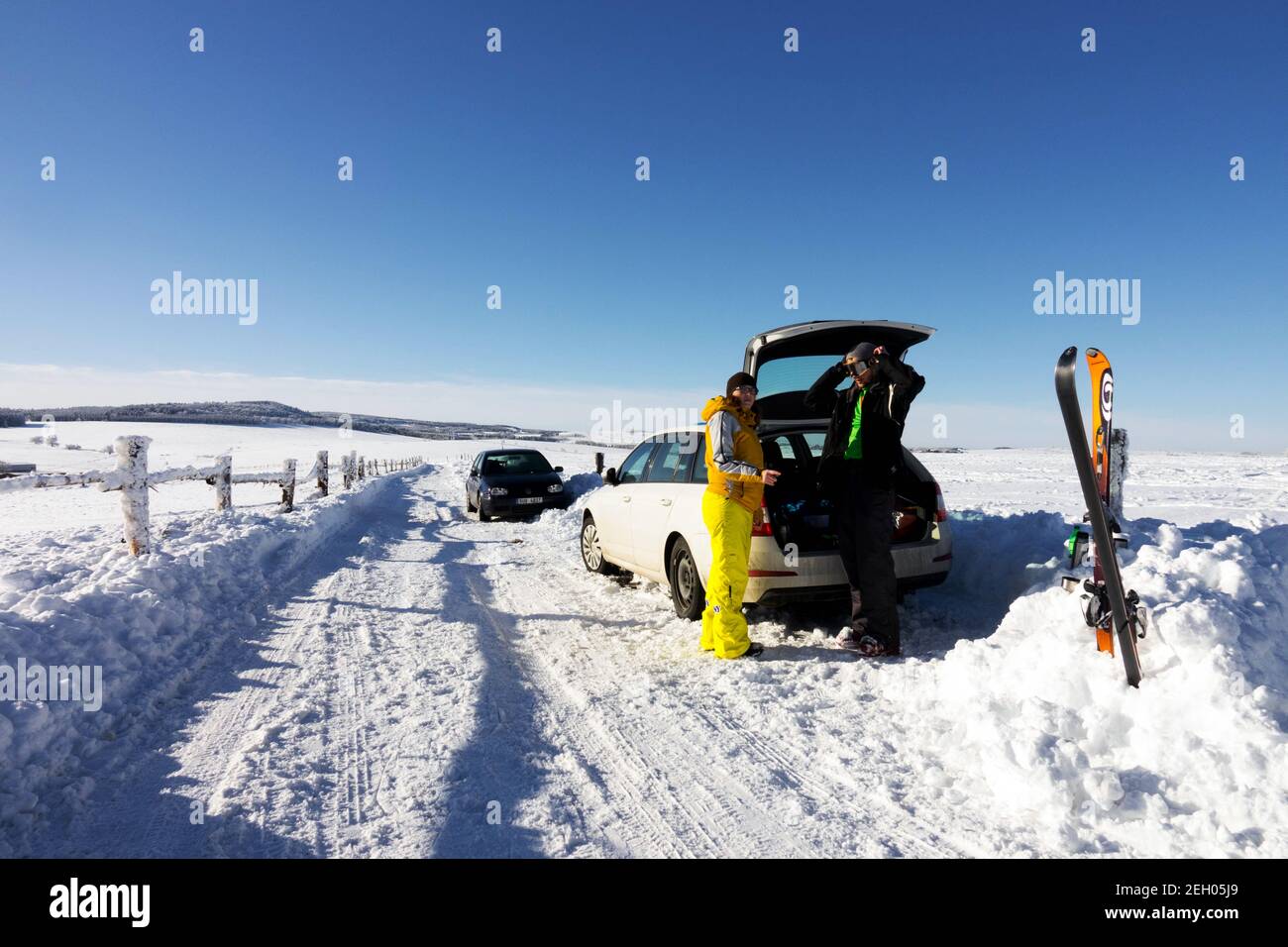 Schneeszene mit Wintersportlern, ein Auto parkt an einer verschneiten Straße, Tschechien Skifahren in den tschechischen Bergen Winterszene Stockfoto