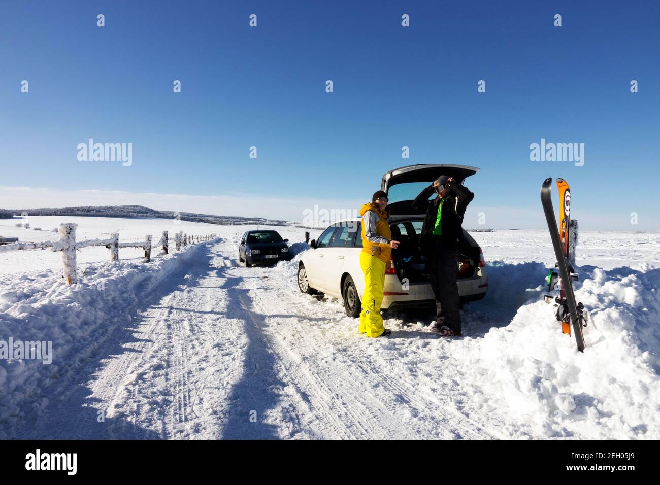 Schneeszene mit Wintersportlern, ein Auto parkt an einer verschneiten Straße, Tschechische Republik Skifahren in den tschechischen Bergen Winterszene Krusne Hory Erzgebirge Stockfoto