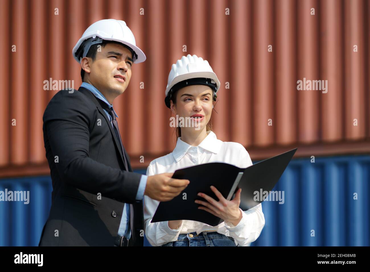 Ein kaukasischer Manager erklärt der Sekretärin das Logistiktransportsystem im Container-Depot-Terminal. Stockfoto