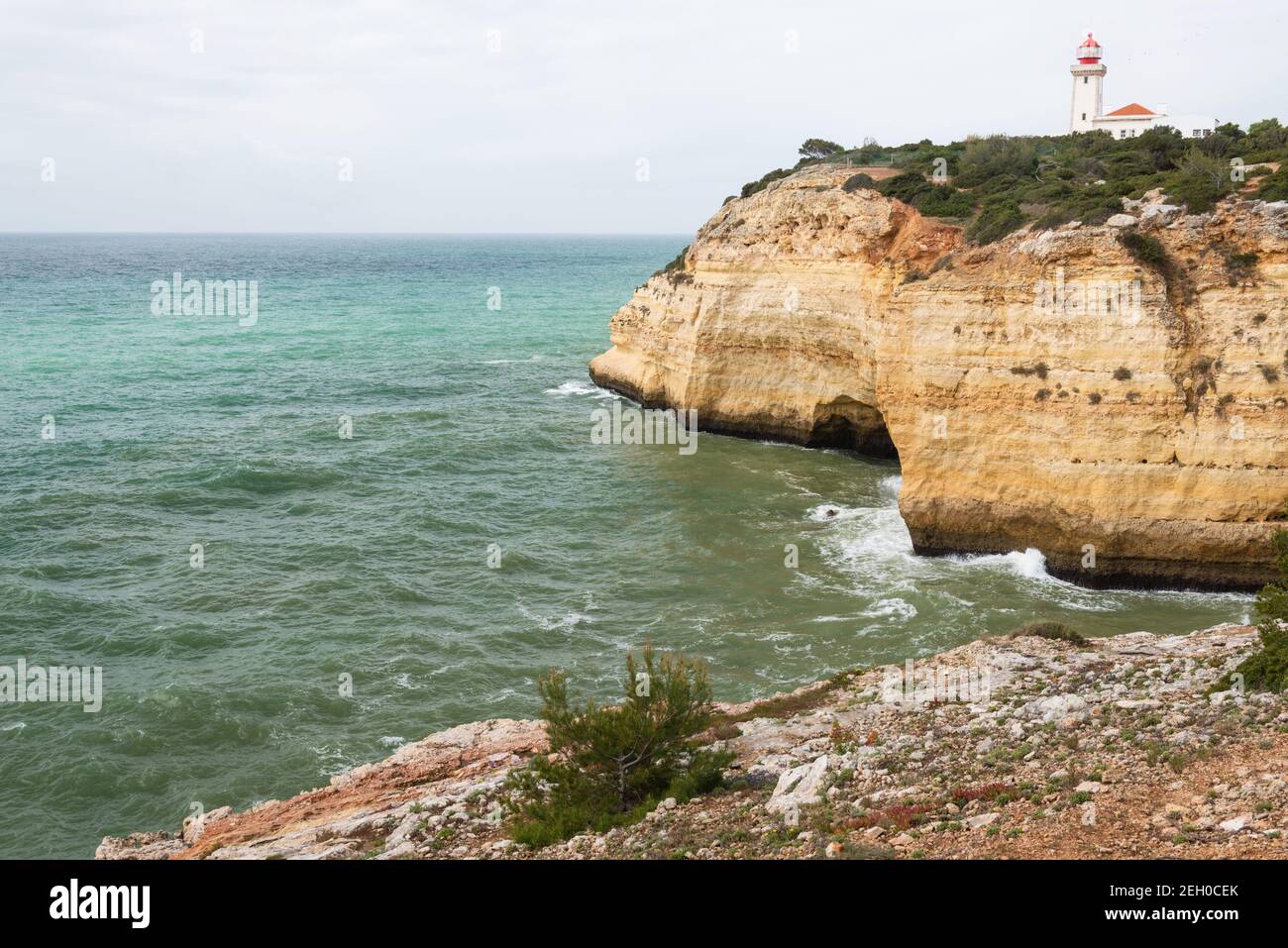 Blick auf die Küste entlang der Seven Hanging Valleys Trail mit Farol de Alfanzina Leuchtturm im Hintergrund, Algarve Region, Portugal Stockfoto