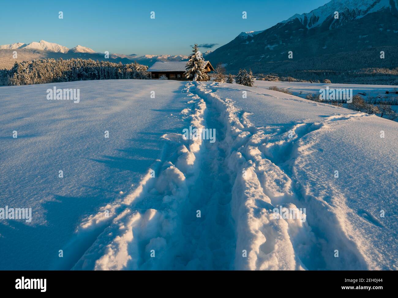 Tiefschneepfad in sonnenbeschienenen alpinen Winterlandschaft bei Sonnenuntergang in Wildermieming, Tirol, Österreich Stockfoto