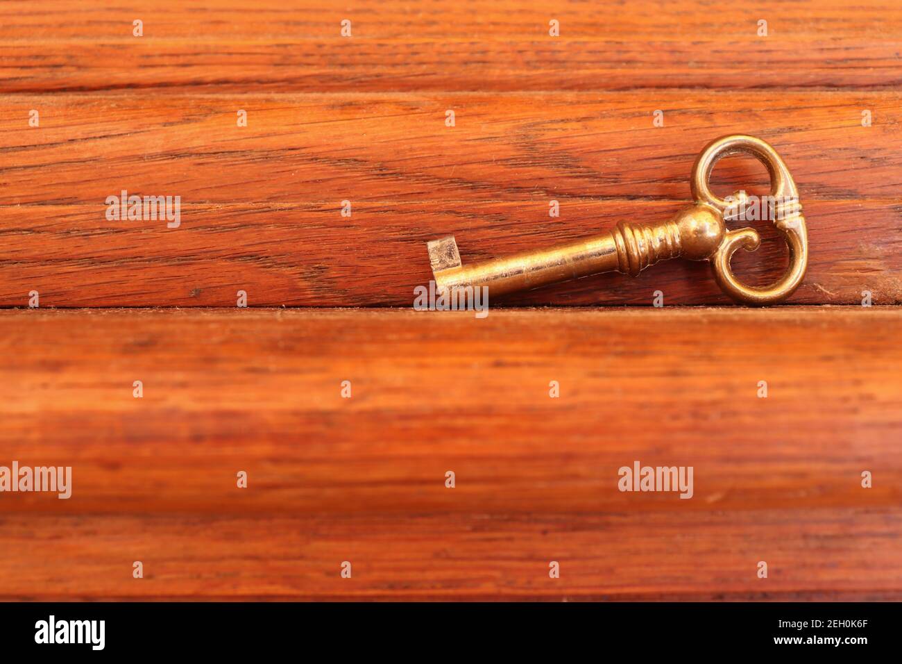Kleiner Schlüssel für eine antike Standuhr, die auf Holz liegt. Stockfoto