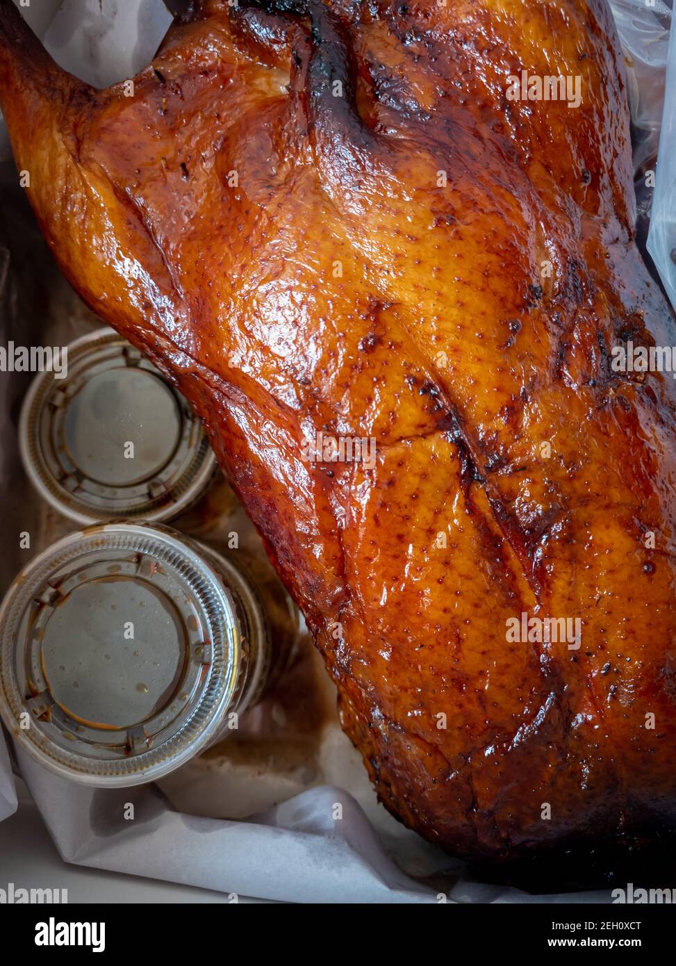Eine kantonesische ganze gebratene Ente mit einem Behälter mit Sauce als Paket zum Mitnehmen. Stockfoto
