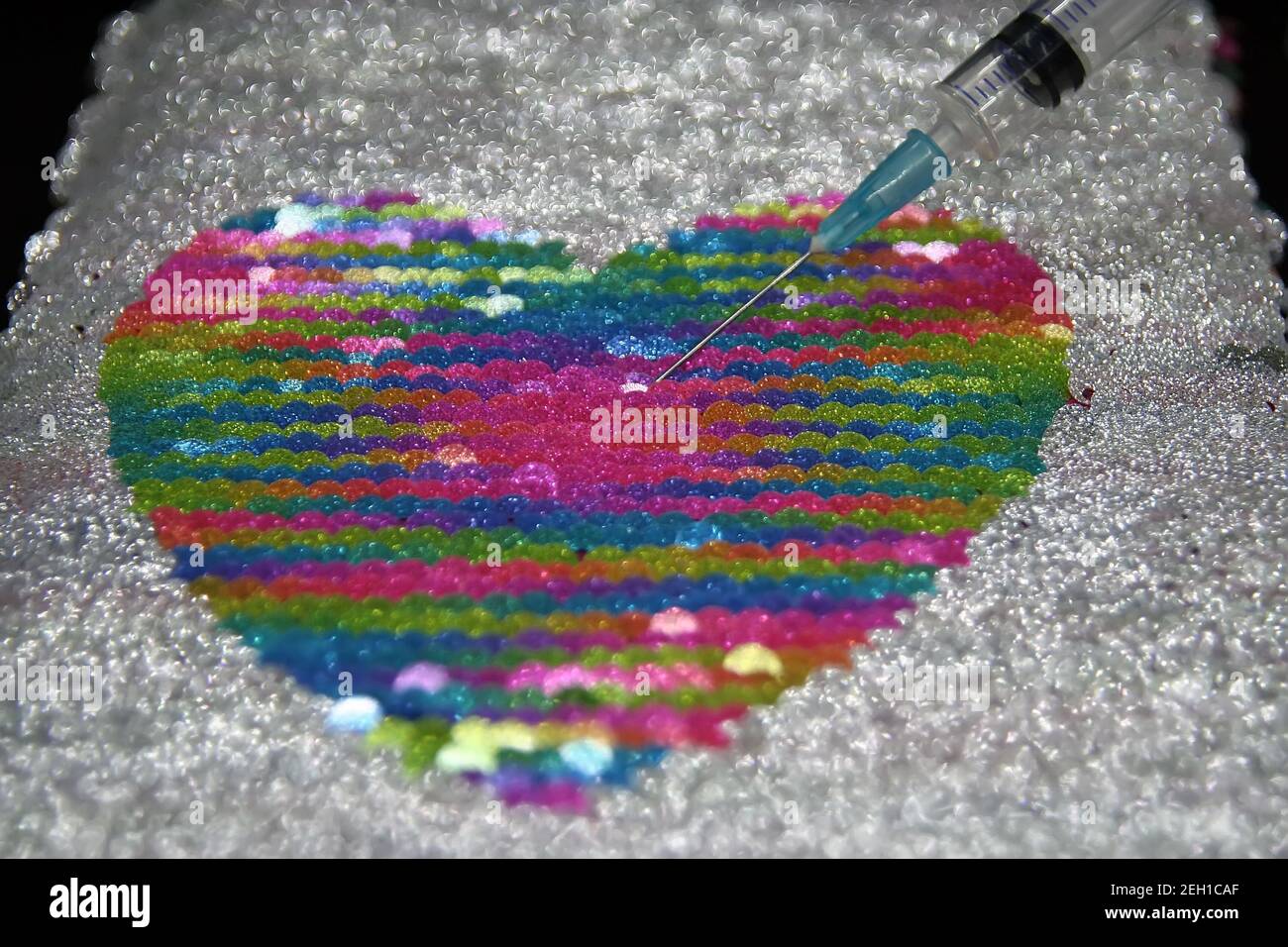 Medizinische Spritze und ein Herz. Herzförmiges Objekt und eine Heilung. Stockfoto