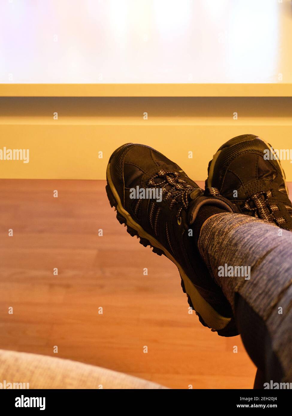 Liegen auf dem Sofa zu Hause in Hausschuhen. Nehmen Sie die Füße vom Sofa, Konzept. Reinigung. Treten Sie nicht auf den Parkettboden. Legen Sie keine Hausschuhe auf Möbel Stockfoto