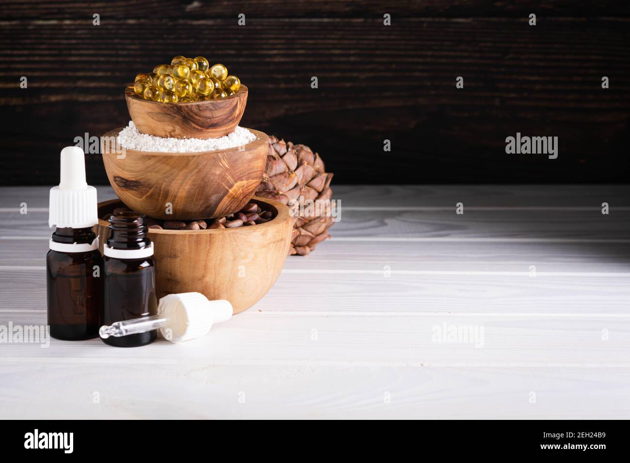Natürliches Produktkonzept, Pinienkerne, Öl, Extrakt auf weißem Holztebel Stockfoto