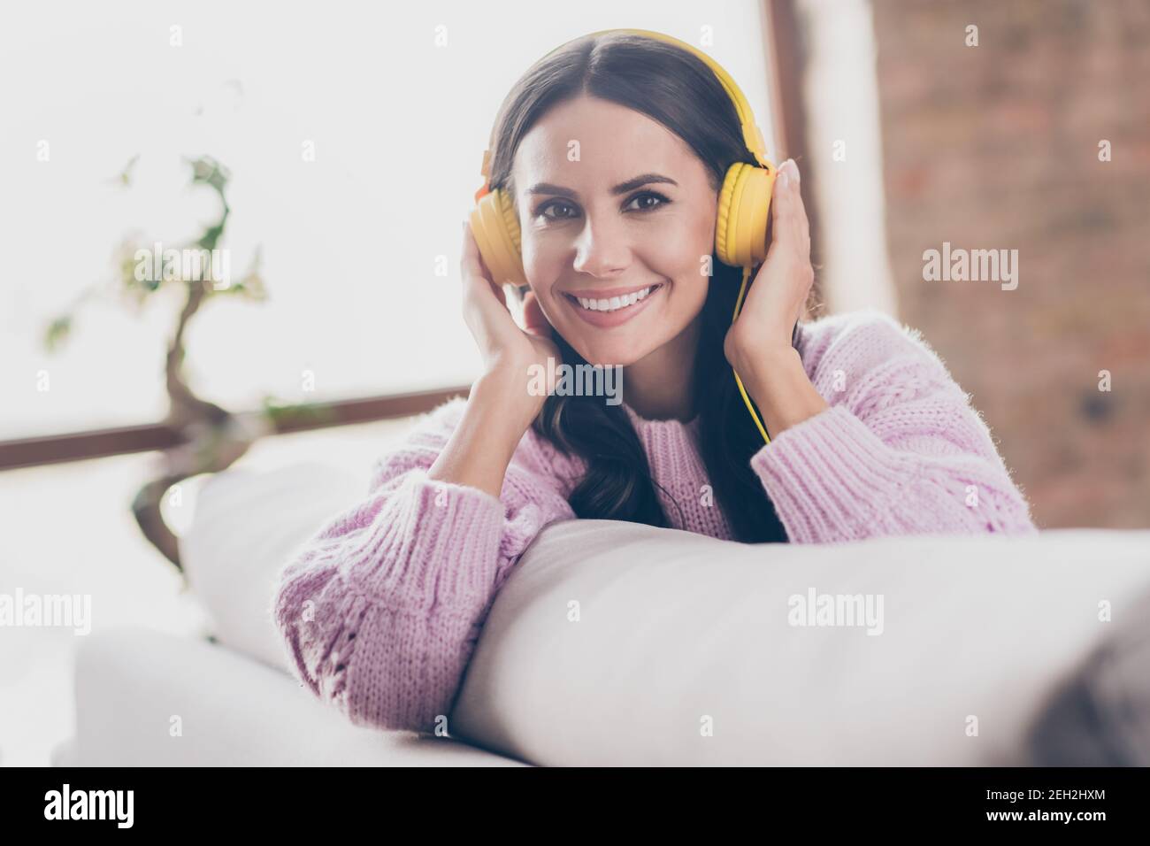Foto von charmanten fröhlich junge Dame hören Musik tragen Kopfhörer Gute Stimmung drinnen im Haus Stockfoto