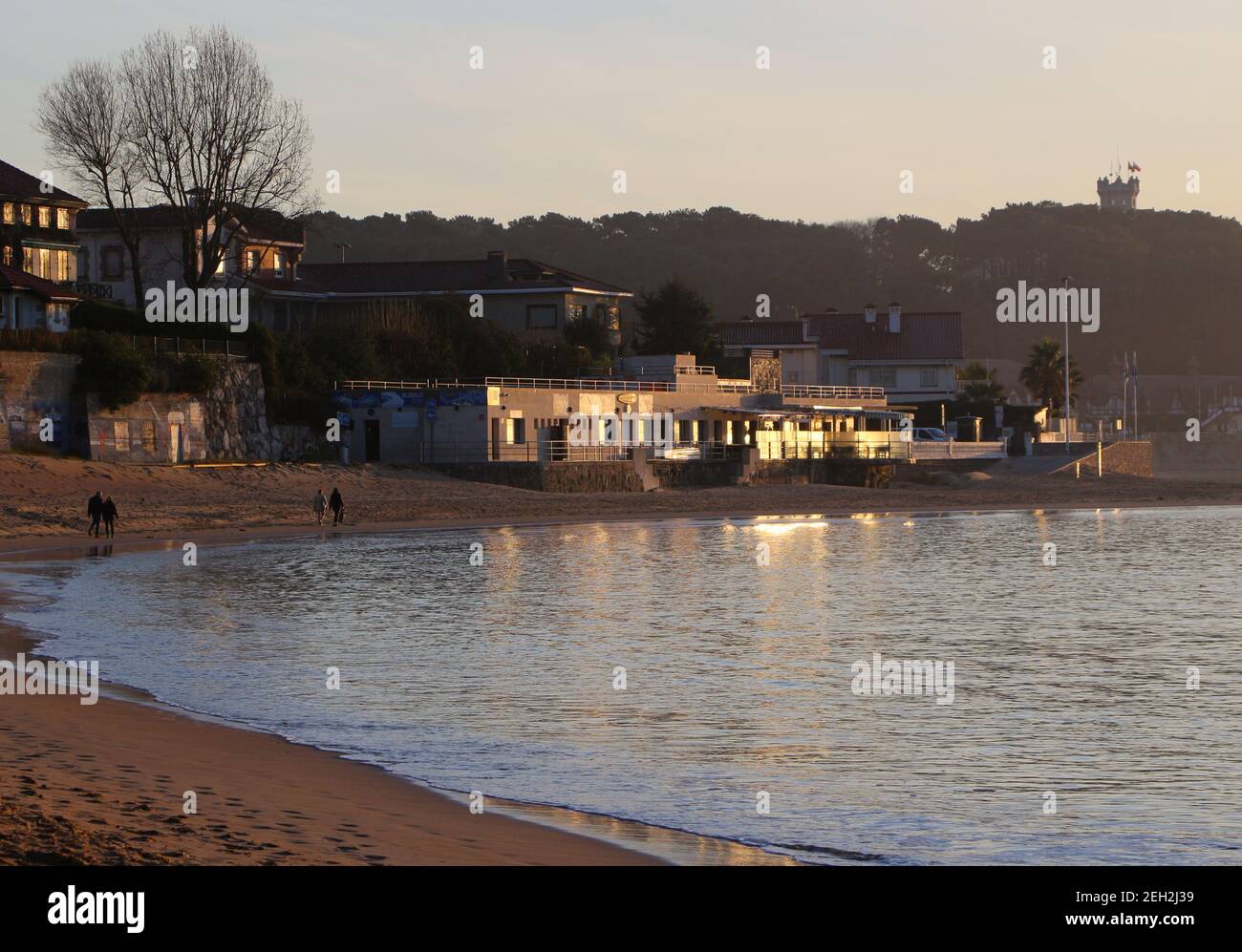 Heterosexuelle Paare, die an einem sonnigen Morgen am Strand Playa de los Bikinis am Rande der Bucht von Santander Cantabria Spanien spazieren gehen Stockfoto Heterosexuelle Paare, die an einem sonnigen Morgen am Strand Playa de los Bikinis am Rande der Bucht von Santander Cantabria Spanien spazieren gehen Stockfoto