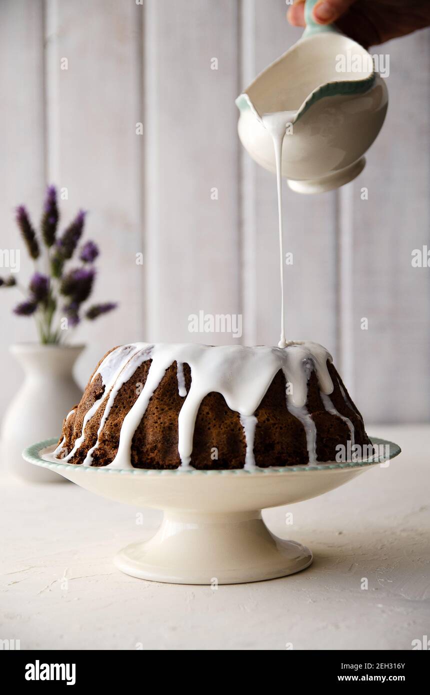 Schokoladenkuchen mit Spitzenverzierung, Lavendelblüten und weißem Hintergrund. Stockfoto