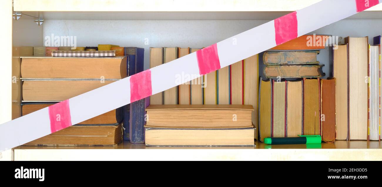 Geschlossene Bibliothek wegen Corona Lockdown, Reihe von Büchern, Bücherregal mit Sperrband, Konzept Stockfoto