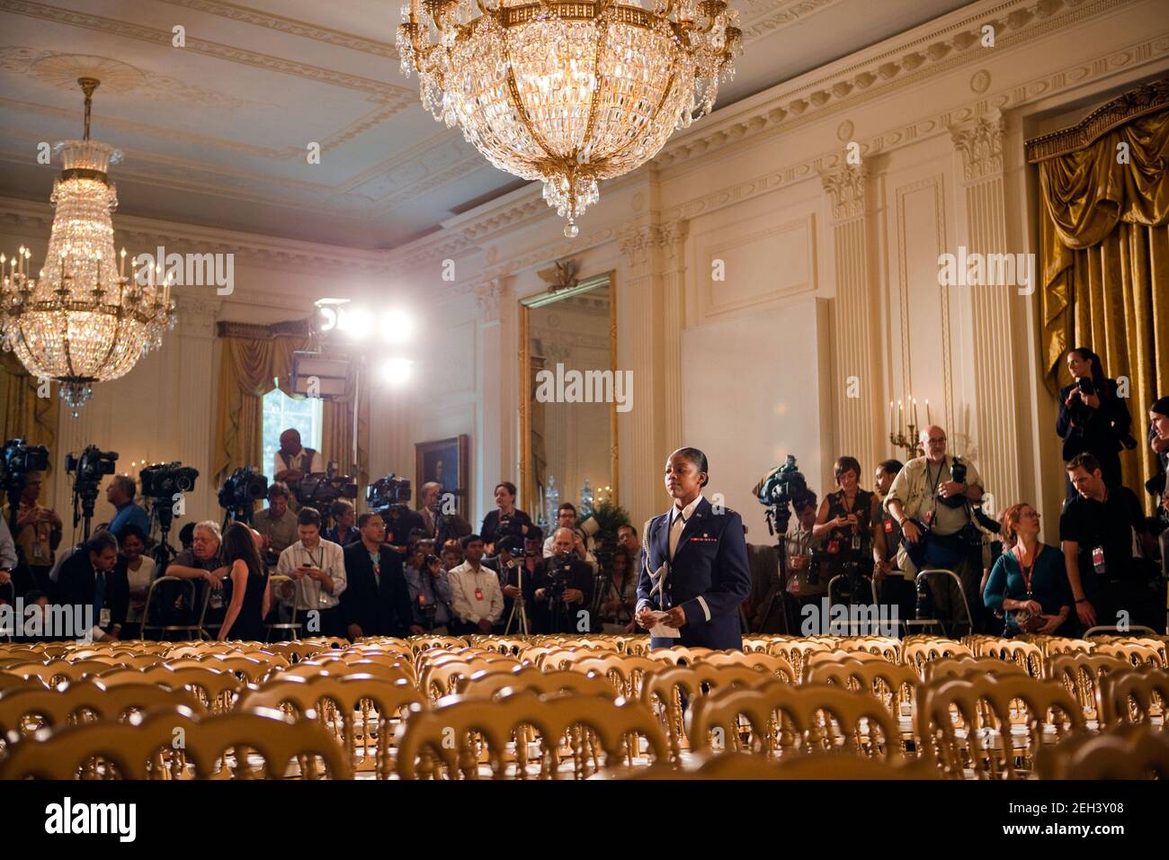 Ein Militärfahrer steht inmitten der Stühle, während sich die Presse im Hintergrund für die Zeremonie zur Medaille der Freiheit im Ostsaal des Weißen Hauses in Washington, 12. August 2009 versammelt. Stockfoto