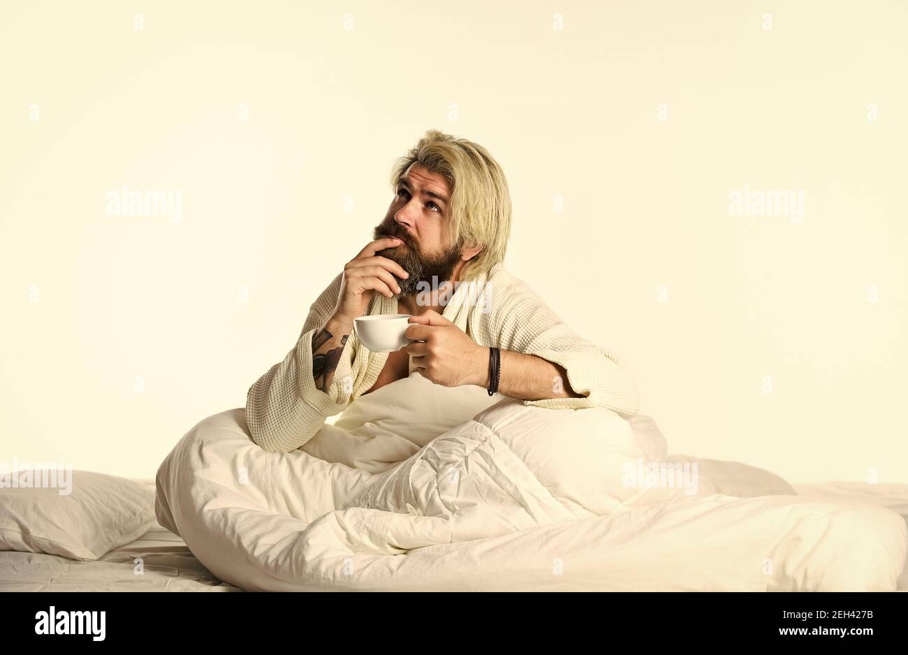 Start Tag mit gutem Kaffee. Gourmet-Espresso. Genießen Sie den morgendlichen Kaffee. Schöner Mann trinkt Kaffee. Reifer bärtiger Mann im Bett. Der Körper wurde von wesentlichen Komponenten für eine gute Gesundheit und Energie beraubt. Stockfoto