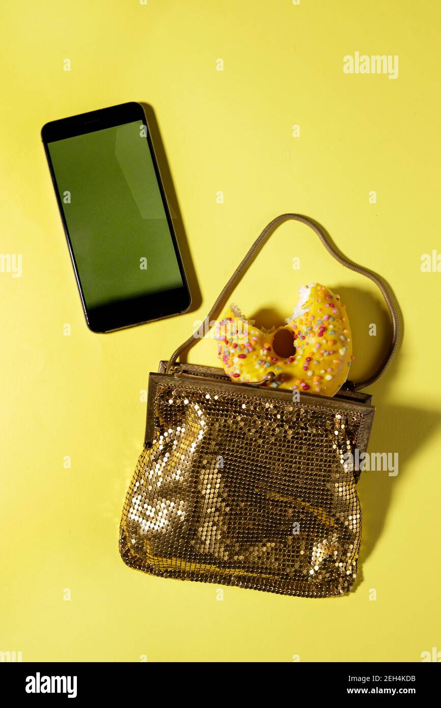 Partytasche mit einem Donut darin und einem Mobile Telefon Stockfoto