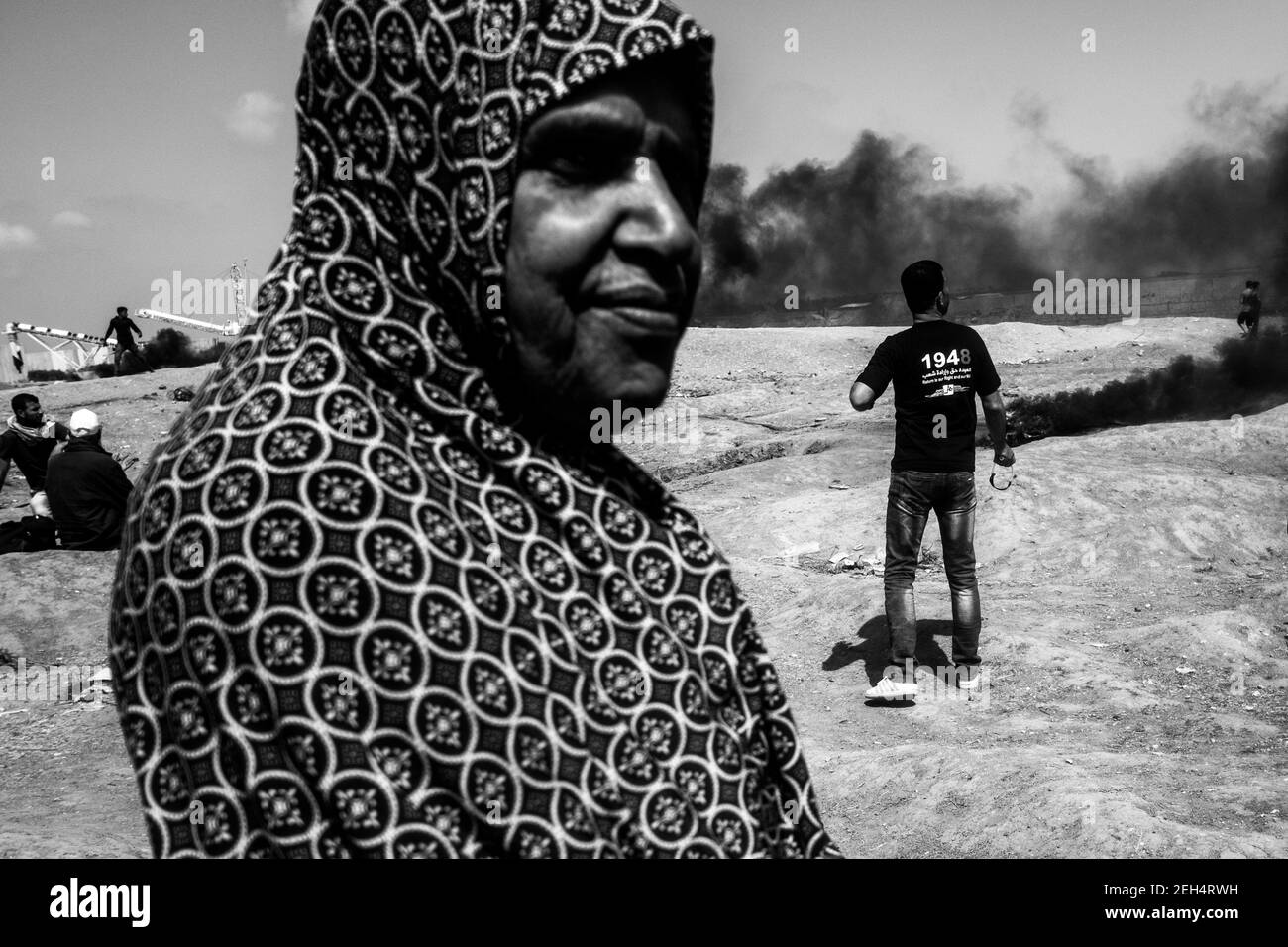Eine Frau beobachtet die Zusammenstöße zwischen palästinensischen Demonstranten und der israelischen Armee. Die Spannungen entlang der Grenze zwischen Gaza und Israel sind nach mehr als einem Monat wöchentlicher Massenproteste in der Nähe der Barriere, bei denen 50 palästinensische Demonstranten getötet und mehr als 1.700 durch israelische Militärfeuer verletzt wurden, hoch. Die Hamas-Führer in Gaza haben versprochen, dass die Märsche fortgesetzt werden, bis die zehnjährige israelische Blockade des Territoriums aufgehoben wird. Proteste werden auch am 14. Und 15. Mai erwartet, dem Tag, an dem die Palästinenser Yawm an-Nakba oder den "Tag der Katastrophe" zum Gedenken an den Jahrestag ihrer Massenentminierung begehen werden Stockfoto