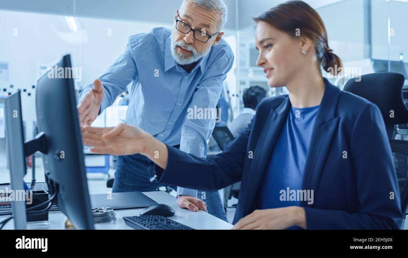 Moderne Fabrik Büro: Project Manager Supervisor Gespräch mit einer weiblichen Ingenieurin arbeiten an Computer. Team von Fachleuten für die Lösung von Problemen in der Schwerindustrie Stockfoto